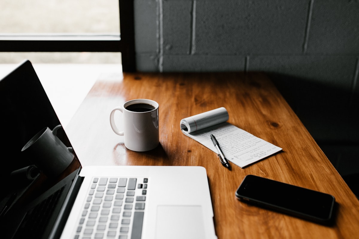 Escritorio de trabajo con notebook, café y apuntes a mano